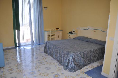 普罗奇达萨沃伊亚酒店的一间卧室配有一张床、一张桌子和一个窗户。