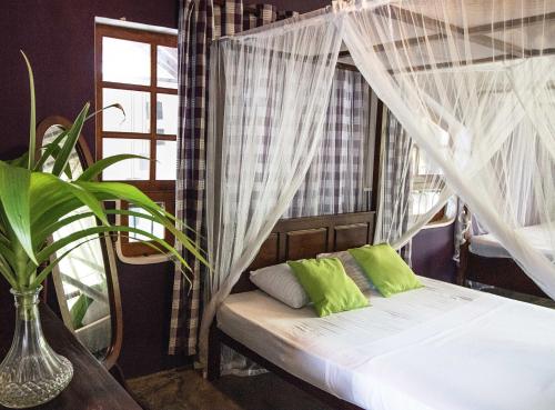 尼甘布维拉塔普洛班住宿加早餐旅馆的一间卧室配有一张带蚊帐的床