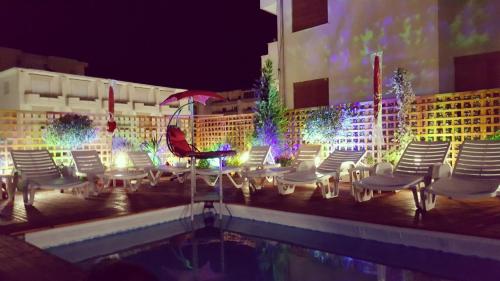 都拉斯Sunrise Hotel Cameria的一组椅子和一个晚上的游泳池