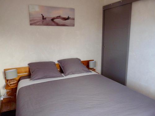 圣吕奈尔Suite à 800m de la plage的卧室配有一张床,墙上挂着一幅画
