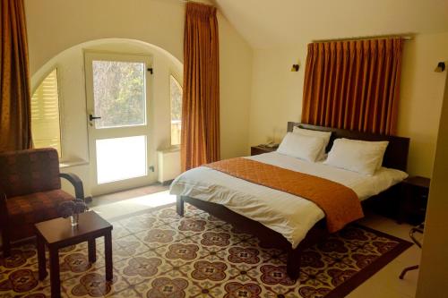 拉马拉Alhambra Palace Hotel Suites - Ramallah的卧室配有床、椅子和窗户。