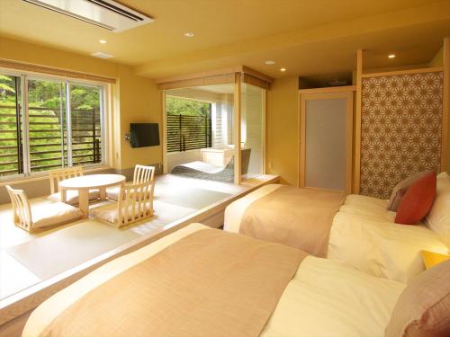 箱根箱根汤宿 然日式旅馆的配有桌子和窗户的客房内的两张床