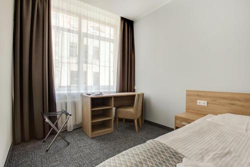维尔纽斯Old Town Trio Hostel Rooms的一间卧室配有一张床、一张书桌和一个窗户。