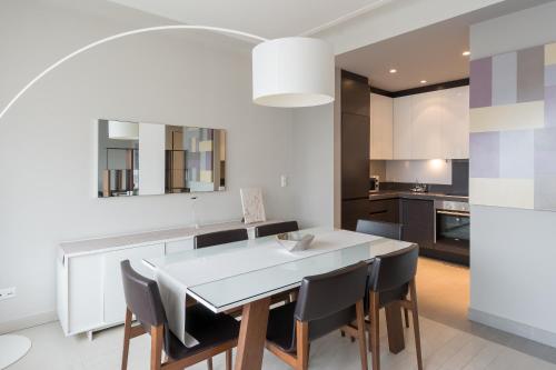 卢森堡四星级公寓式酒店的厨房以及带白色桌椅的用餐室。