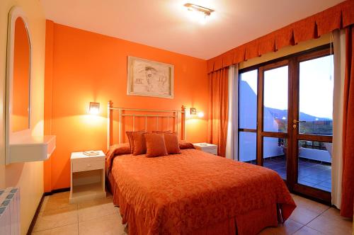 梅洛Terrazas de Merlo Aparts con servicios的一间卧室拥有橙色的墙壁、一张床和窗户