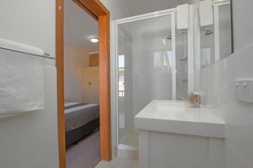 巴利纳河街汽车旅馆的白色的浴室设有水槽和淋浴。