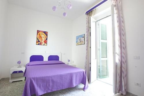 蓬扎Casa Baia Luna的白色卧室设有紫色的床和窗户