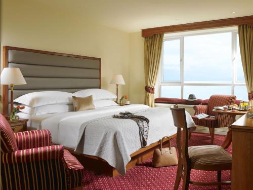 戈尔韦戈尔韦海湾会议及娱乐中心酒店的酒店客房,配有一张床和两把椅子