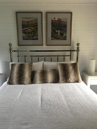 Blayney德瑞诗小屋旅馆的卧室配有一张白色床,墙上挂有两张照片