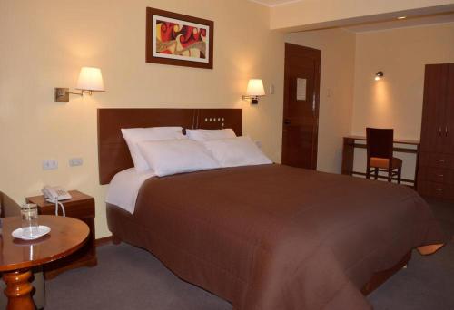 HuancavelicaIllariy Hotel的酒店客房设有一张大床和一张桌子。
