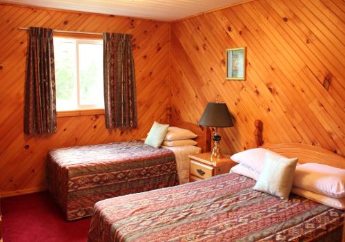 卡文迪西隐秘园地山林小屋的配有木墙和窗户的客房内的两张床