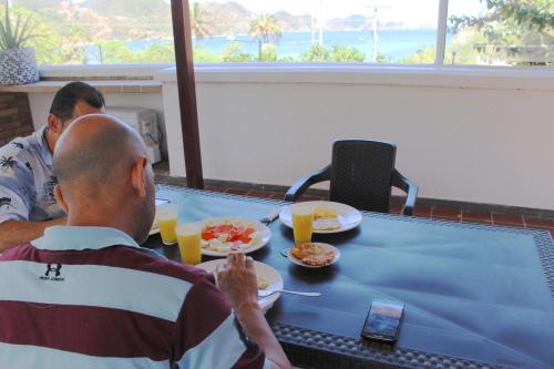 塔甘加Hotel San Marcos Taganga的坐在桌子旁的两个人,拿着食物和橙汁