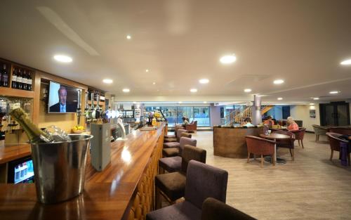 曼彻斯特水边酒店和休闲俱乐部的酒吧设有长木柜台和椅子