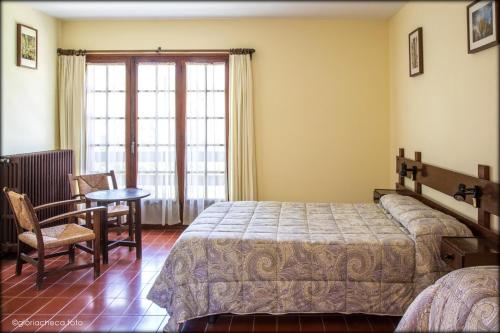 Santa Fe de MontsenyHostal l'Avet Blau的卧室配有1张床、1张桌子和1把椅子