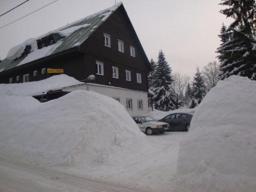 约瑟夫杜尔Horsky hotel Sport的一所房子和两辆汽车旁边堆积雪