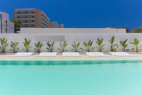 伊维萨镇白色公寓 - 仅限成人入住的游泳池旁的一排白色长椅