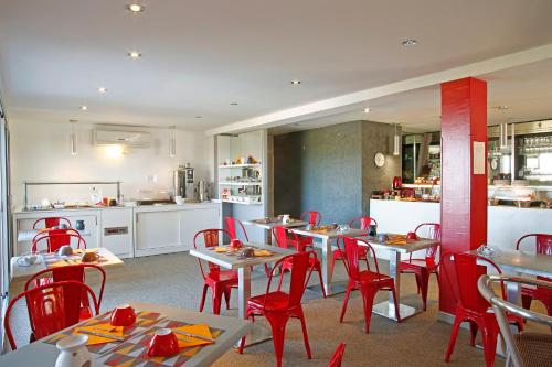 利勒鲁斯海滨喷泉酒店的一间带桌子和红色椅子的餐厅和一间厨房
