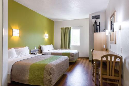 雪松城锡达城6号汽车旅馆的酒店客房设有两张床和一张桌子。