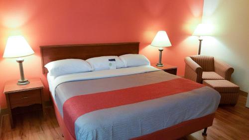 马里兰高地Motel 6-Maryland Heights, MO的一间卧室配有一张带两盏灯和一把椅子的床。