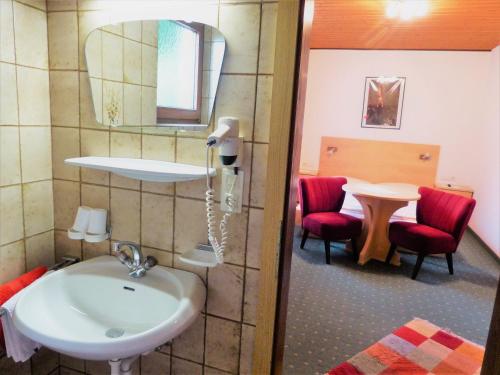 弗林肯贝格豪斯阿斯特丽德克里斯托夫酒店的一间带水槽和一张红色椅子的桌子的浴室