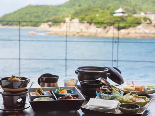 福山米格瓦特欧驰卡慈酒店的餐桌,餐桌上放着食物盘,靠近水面