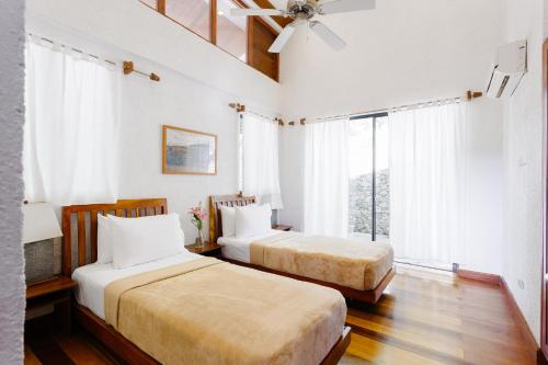 长滩岛The Strand Boutique Resort的一间卧室配有两张床和吊扇