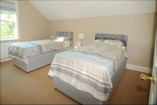 BellaghyHomeplace Retreat Bellaghy Top Rated Property for Families Min 2 nights的一间卧室设有两张床和窗户。