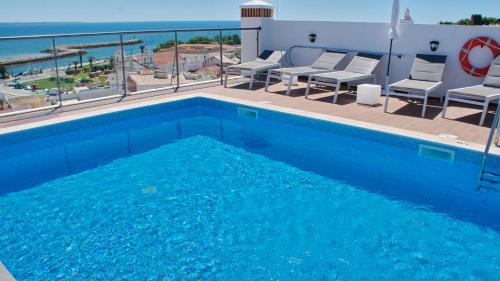 拉戈斯Topcity Hostel & Suites的一个带椅子的游泳池,享有海景