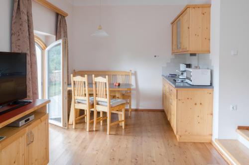 林茨瓦尔德波斯加特公寓的厨房配有木制橱柜和桌椅