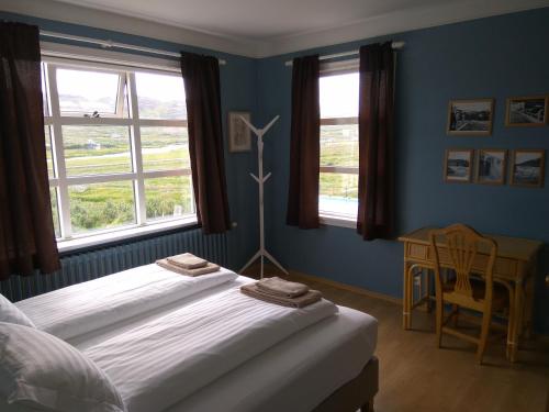 侯尔马维克Hótel Laugarhóll with natural hot spring的一间卧室配有一张床、一张书桌和两个窗户。