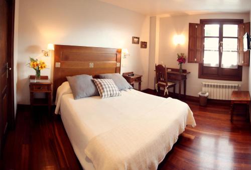 CacesCasa de Aldea La Pumariega的卧室配有一张白色大床和一张书桌