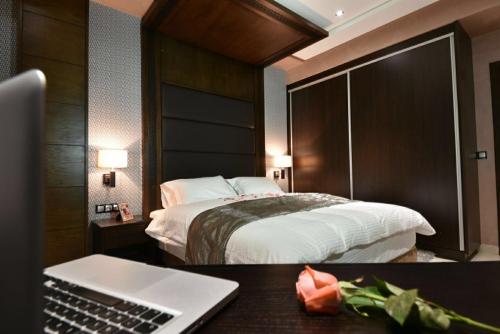 萨伊迪耶Bellington Appart Hôtel的酒店客房配有一张床铺和一张书桌上的笔记本电脑