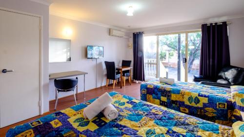 Australind澳大利恩假日公园的酒店客房配有一张床铺、一张桌子和一张书桌。