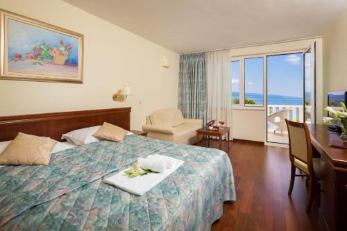 巴什卡沃达Hotel Villa Bacchus的酒店客房设有一张带桌子的床和一个阳台