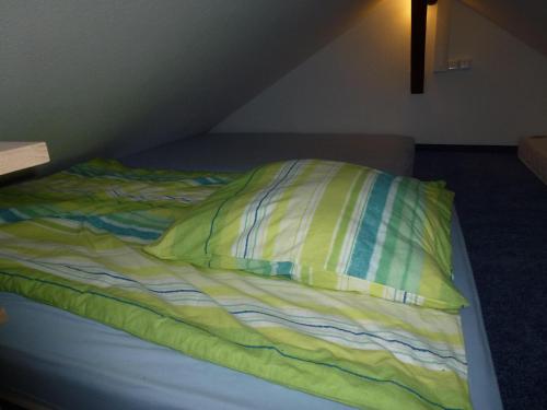 普福尔茨海姆Ferienhaus im Nordschwarzwald的一张未铺好的床,上面有黄色枕头