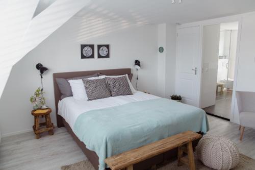 德比尔特Studio De Bilt的白色卧室设有一张带木凳的大床