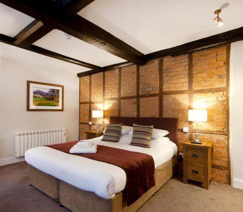 莱德伯里The Talbot Hotel的一间卧室设有一张大床和木墙
