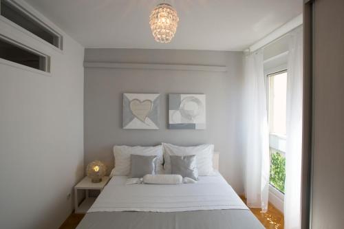 斯普利特拉纳公寓的白色卧室配有一张床和一个吊灯