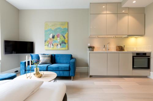 卑尔根2 Døtre Apartments的一间带蓝色沙发的客厅和一间厨房