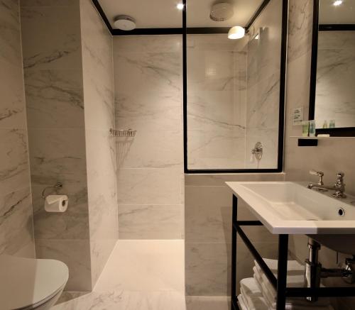 扎芬特姆布鲁塞尔机场逍遥游一室公寓的白色的浴室设有水槽和淋浴。