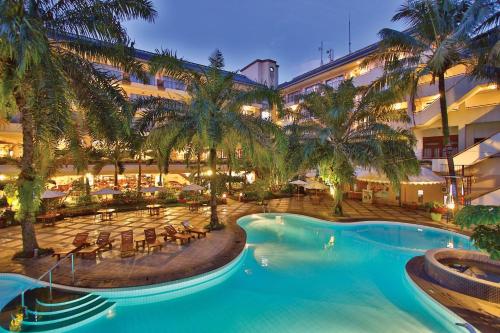 万隆The Jayakarta Suites Bandung的一座拥有游泳池和棕榈树的酒店