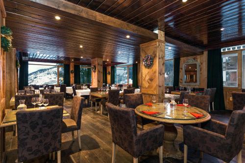 美贝尔Madame Vacances Hôtel & Spa Le Mottaret的餐厅拥有木墙和桌椅