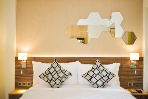 当格浪金色郁金香基本丹格朗酒店的卧室配有带枕头和灯的白色床。