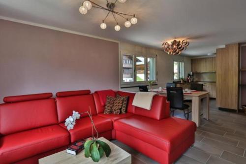 维尔德豪斯Wildhaus Weiherhof的一间带红色沙发的客厅和一间厨房
