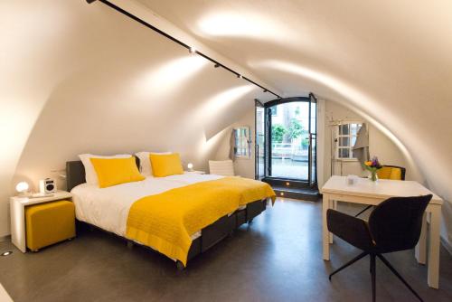 乌得勒支Hotel Oudegracht的一间卧室配有一张带黄色枕头的床和一张书桌