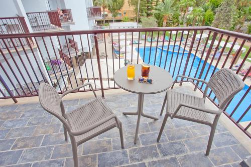 帕尔马诺瓦百慕大费格斯酒店的阳台上配有一张桌子和两把椅子,并备有两杯饮料