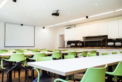 弗莱堡FT Hotel的一个配有桌子和绿色椅子的空教室