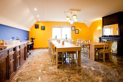 Herzele赫泽勒香格里拉住宿加早餐旅馆的用餐室设有黄色的墙壁和木桌及椅子