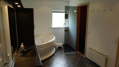 埃贝尔托夫特Three-Bedroom Holiday Home in Ebeltoft的浴室配有白色浴缸和水槽