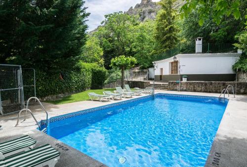 卡索拉Villa Turística de Cazorla的一个带椅子的游泳池以及一座房子